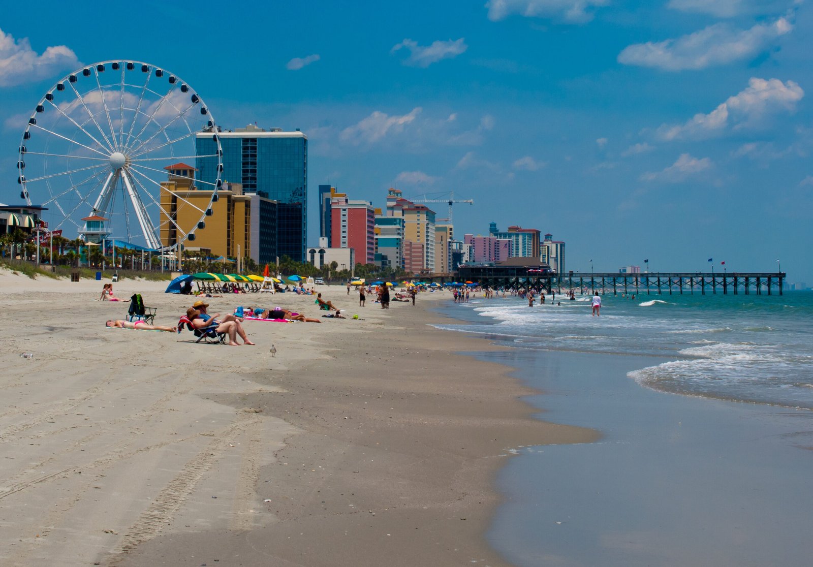 Shoreline of Myrtle Beach, south carolina, showing the ferris wheel, people relaxing on the beach and many colorful condos and sky rise buildings lining the shoreline. copy space available. all faces have been blurred out