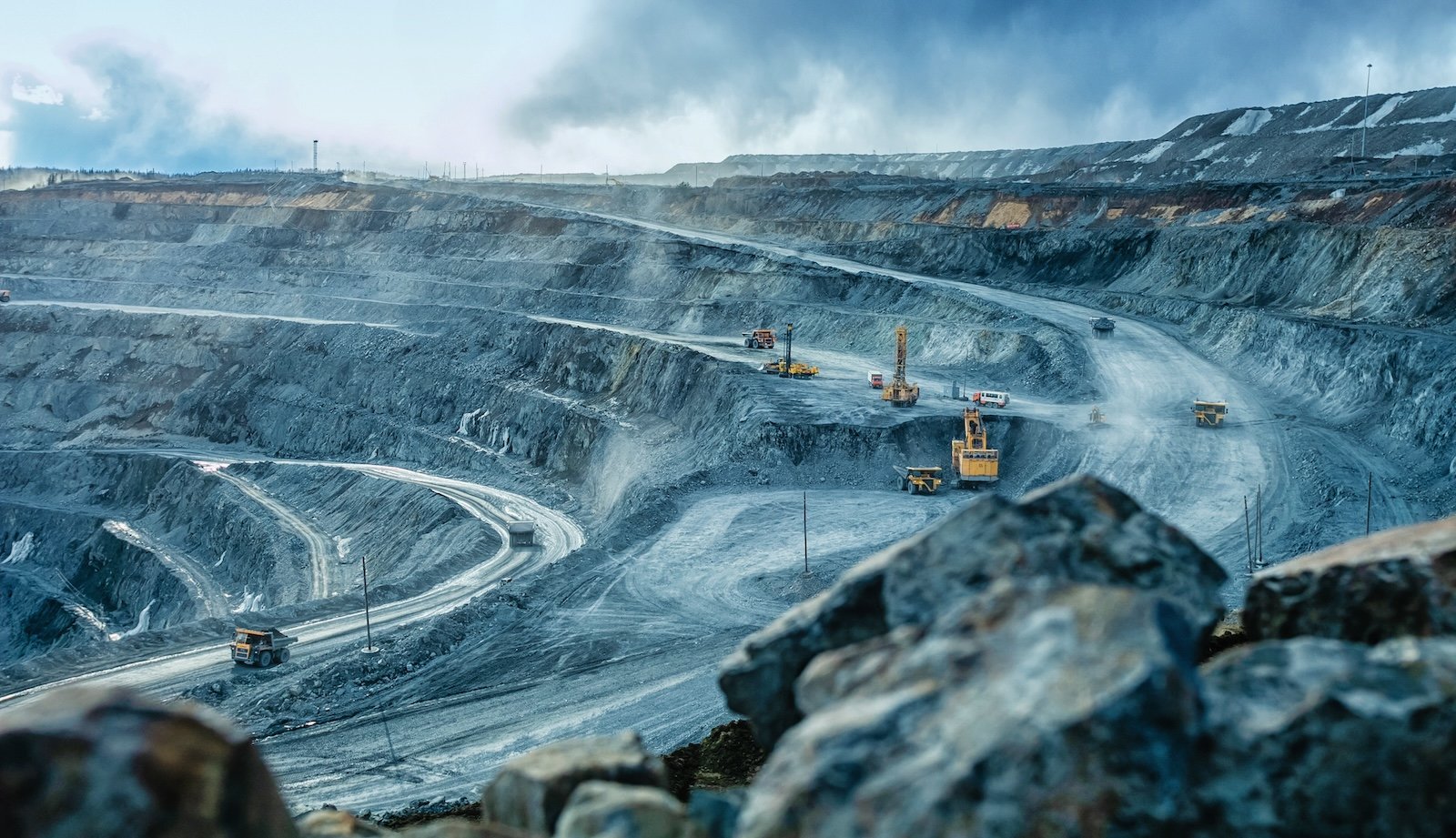 Work of trucks and the excavator in an open pit on gold mining, soft focus